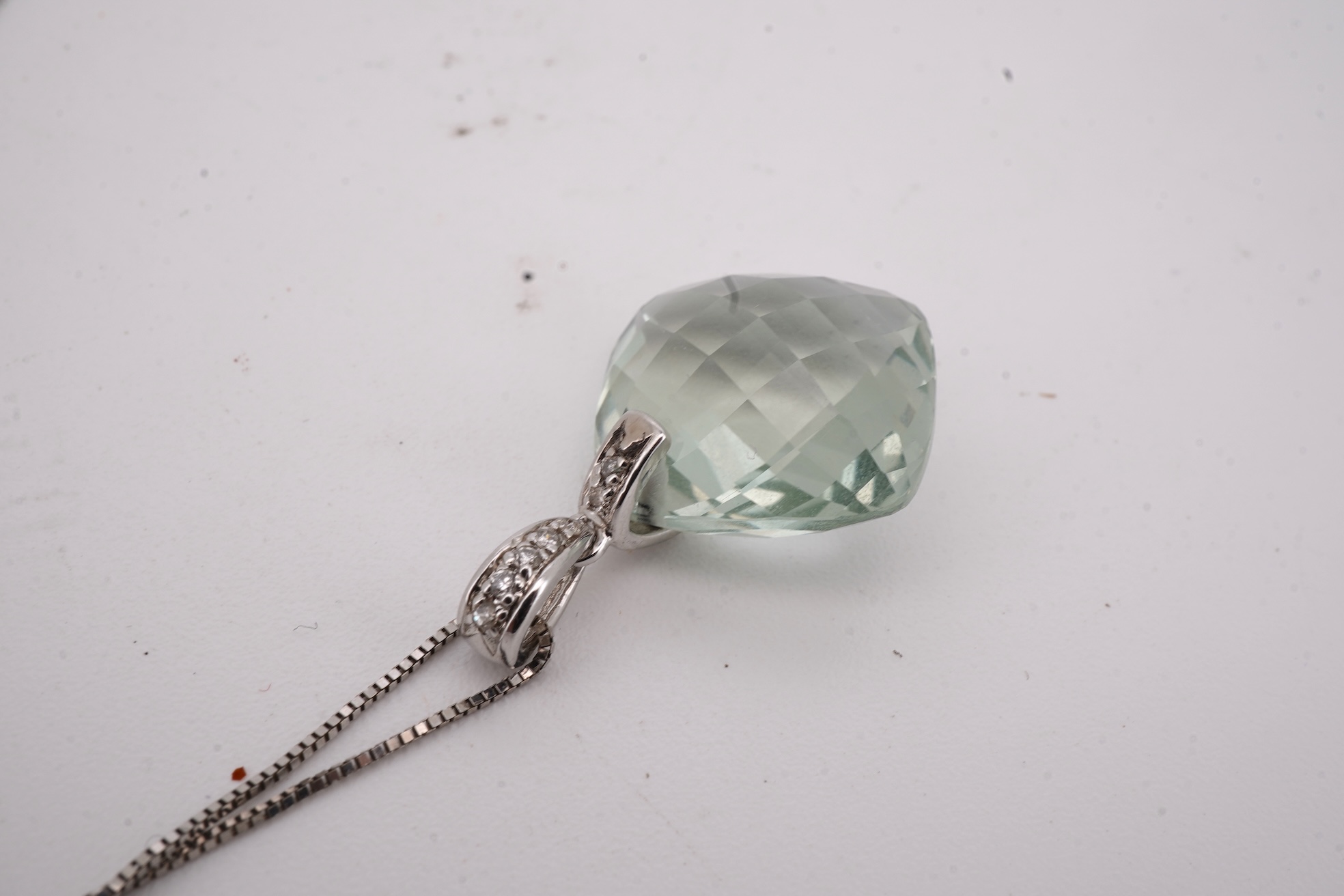 A prasiolite and diamond pendant, the diamond-set bail suspending a cushion-shaped chequerboard-cut prasiolite, to a fine link chain, mounted in 14ct gold, pendant length 2.5cm, chain length 46cm, British hallmarks, gros